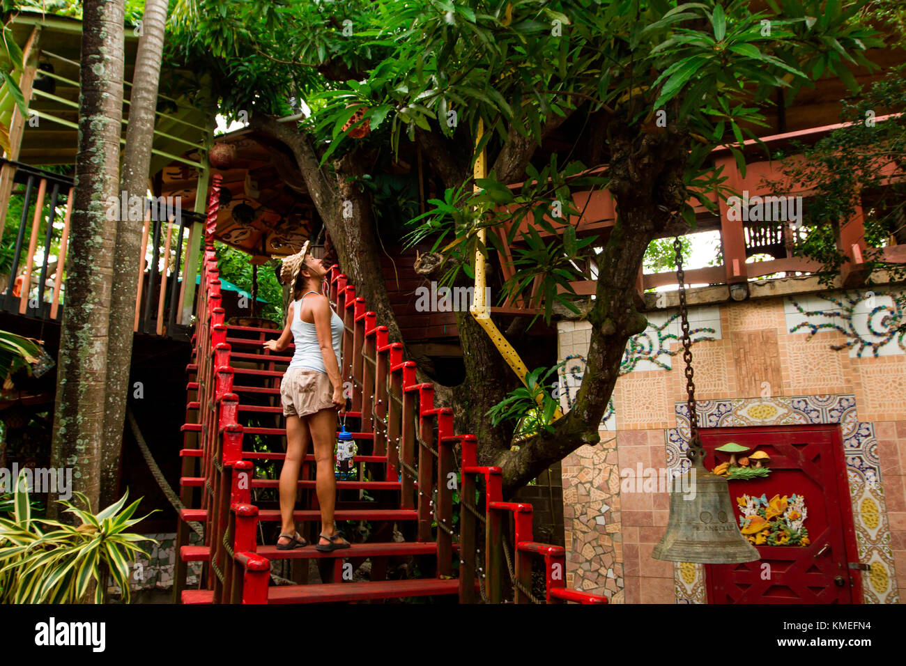 Donna in hat stando in piedi sulla scala rossa, Utila Island, Honduras Foto Stock