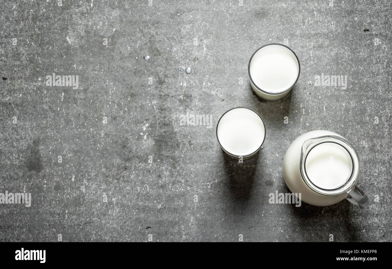 Brocca e bicchieri di latte. sul tavolo di pietra. Foto Stock