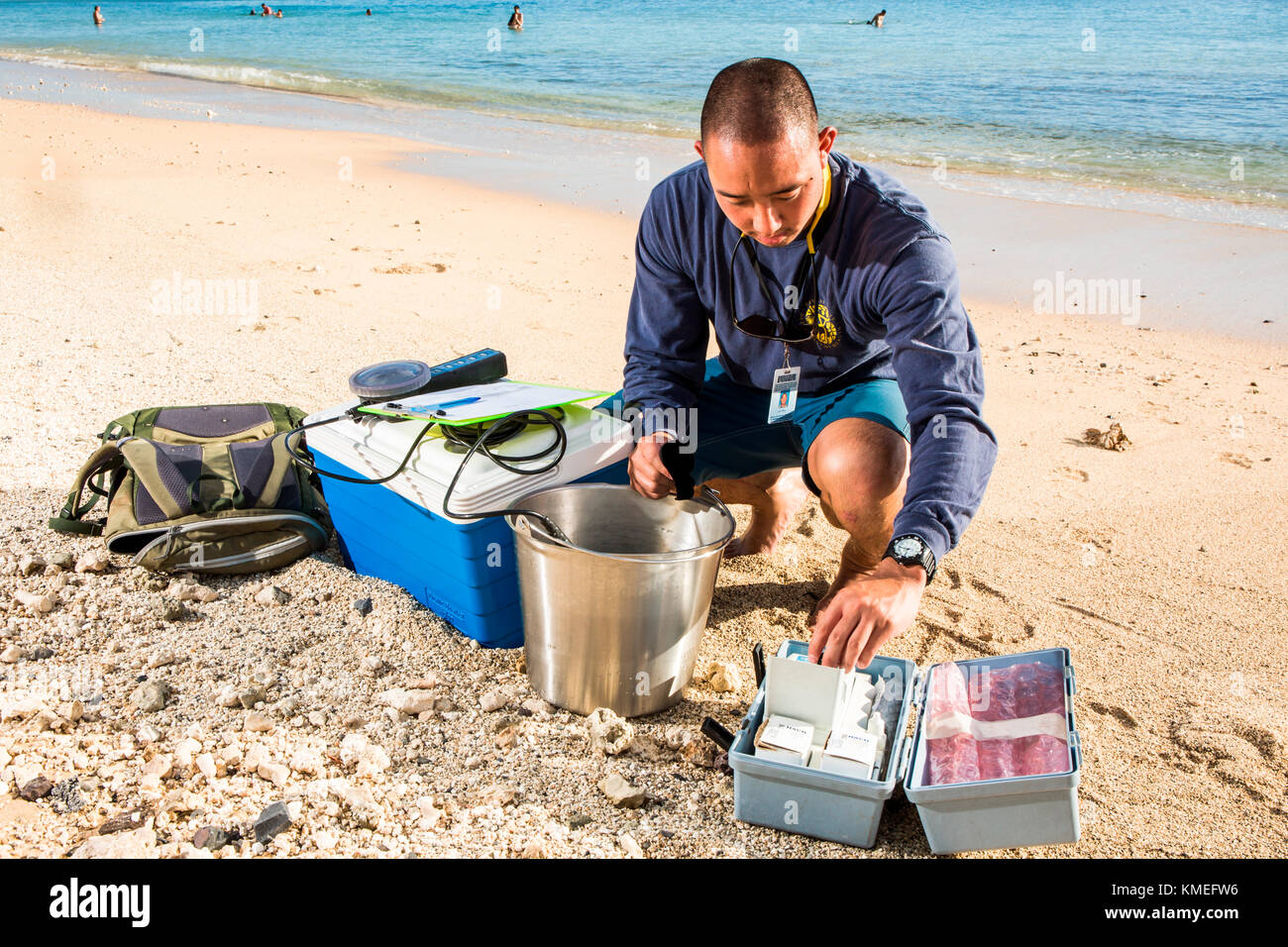 Wataru Kumagai dello Stato delle Hawaii Dipartimento di Salute acqua pulita Branch, dimostra il campionamento delle acque delle spiagge hawaiane ad Ala Moana Beach a Honolulu utilizzando strumenti come un torbidità metro.per l'ambito completo delle letture, il lavoro di laboratorio è fatto fuori sede. Foto Stock
