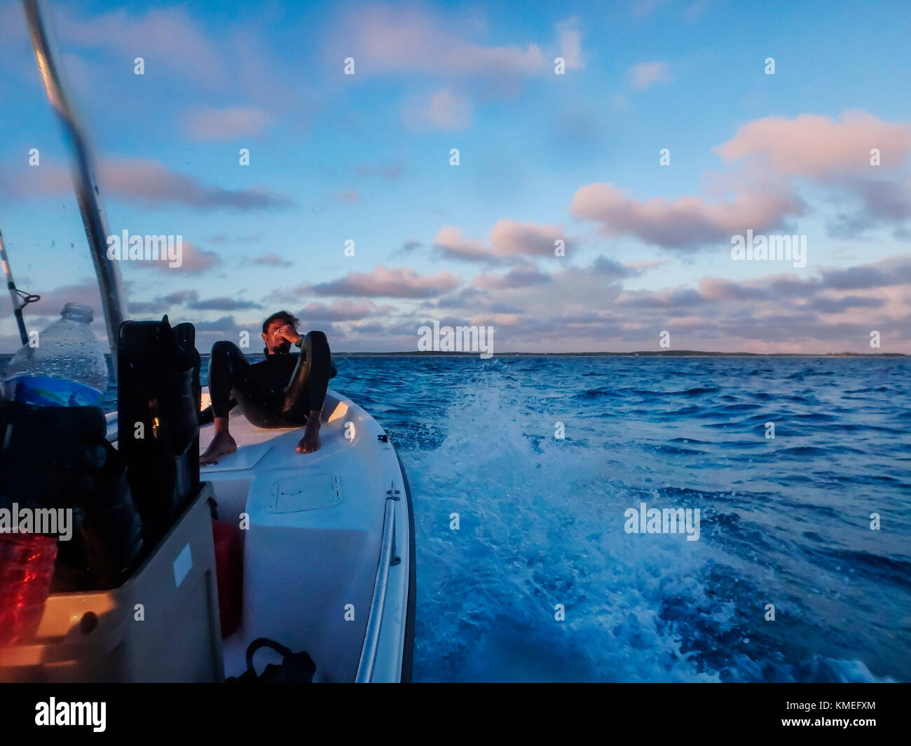 Il subacqueo riposa sull'arco della barca mentre si ritorna dalla pesca di punta e dal viaggio di freewiving, Clarence Town, Long Island, Bahamas Foto Stock