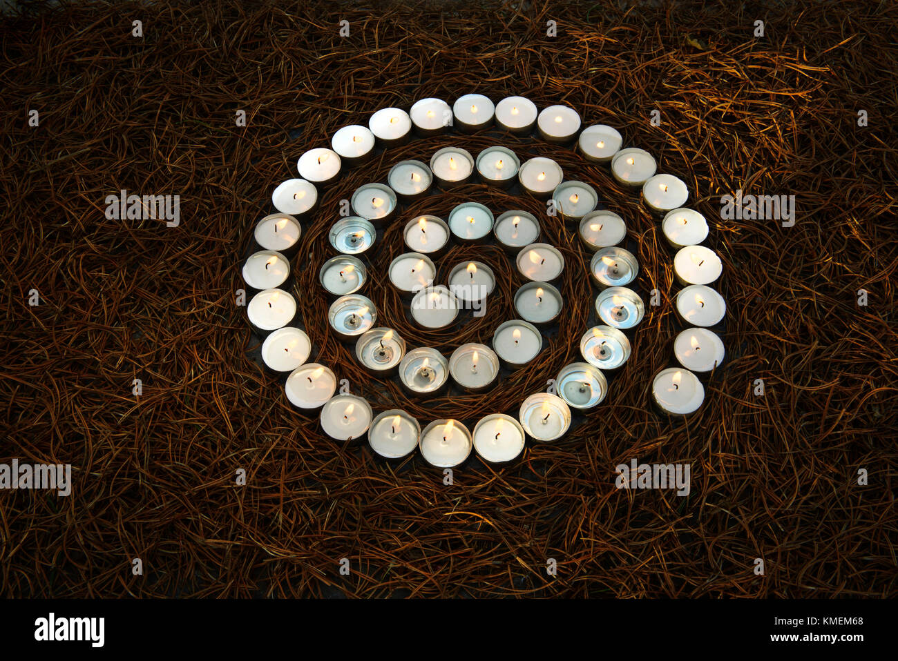 Spirale di tè accesa la luce delle candele su essiccato aghi di pino Foto Stock