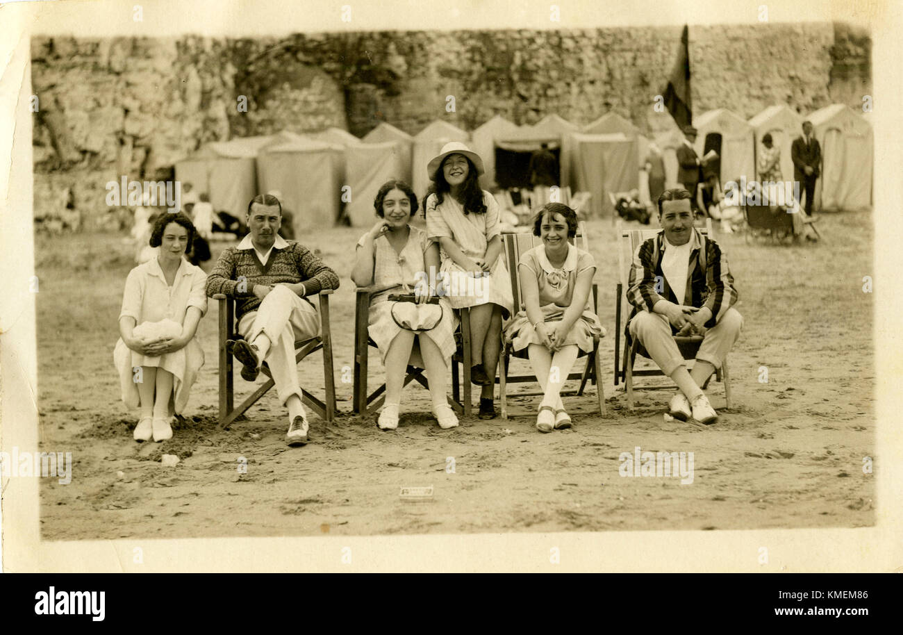 1920s, storico, happy holiday ritratto di famiglia sulla spiaggia che mostra il vestito e la moda del giorno e tela tende di balneazione per la modestia dietro, Inghilterra, Regno Unito. Foto Stock