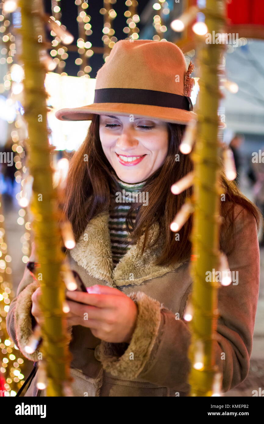 Ragazza utilizzando il telefono cellulare nel festoso ambiente illuminato Foto Stock