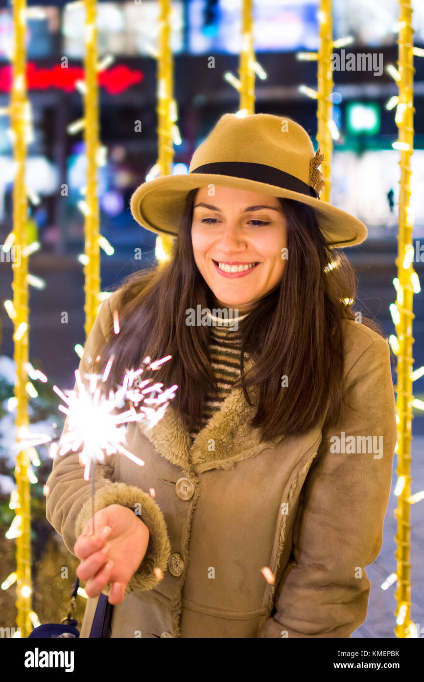 Ragazza con il fuoco brilla con festosa sfondo illuminato Foto Stock