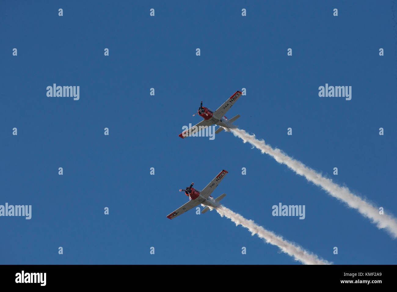 Due aeroplani a elica volare insieme con fumo trail nel profondo blu del cielo Foto Stock