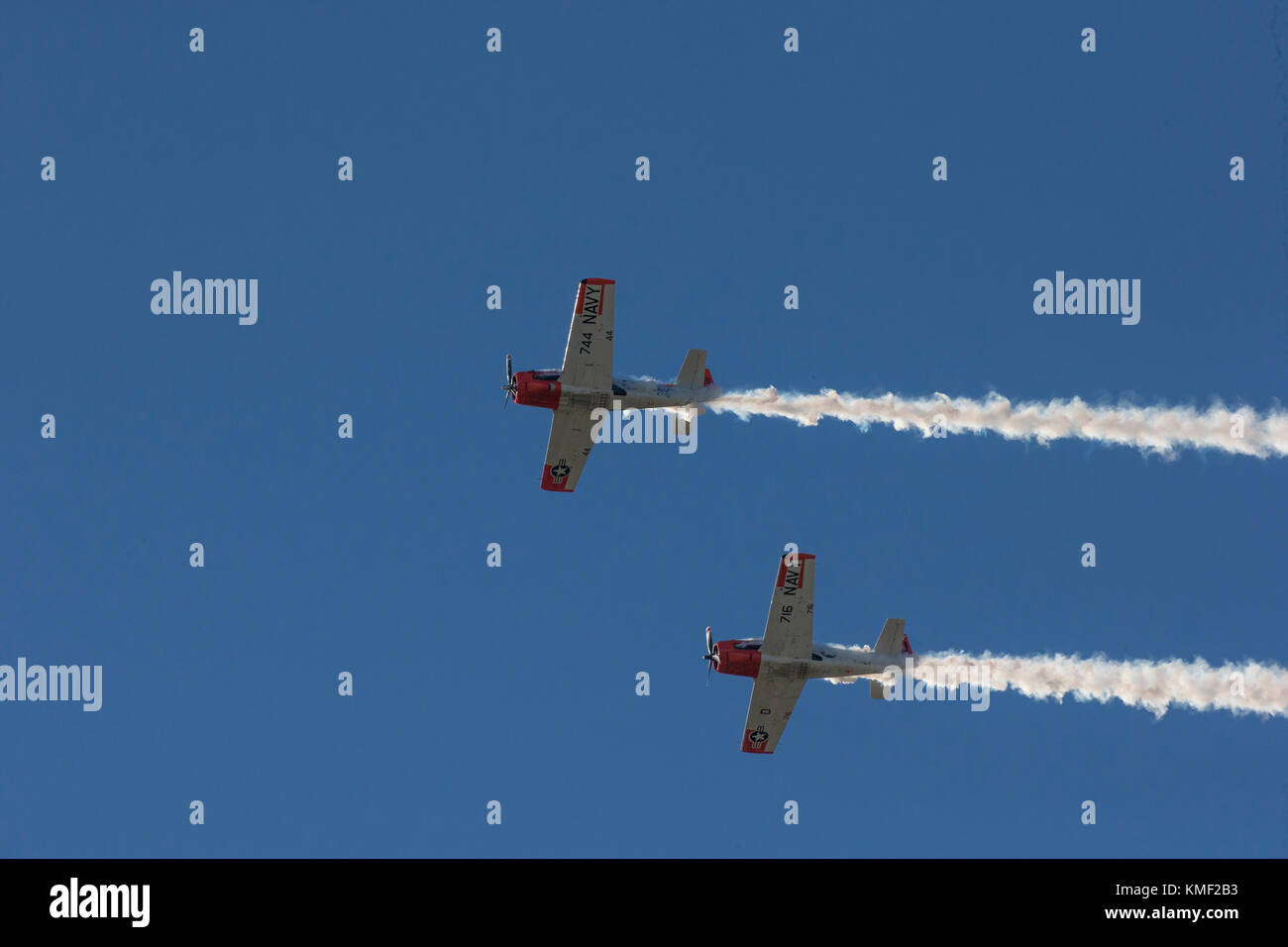 Due aeroplani a elica volare insieme con fumo trail nel profondo blu del cielo Foto Stock