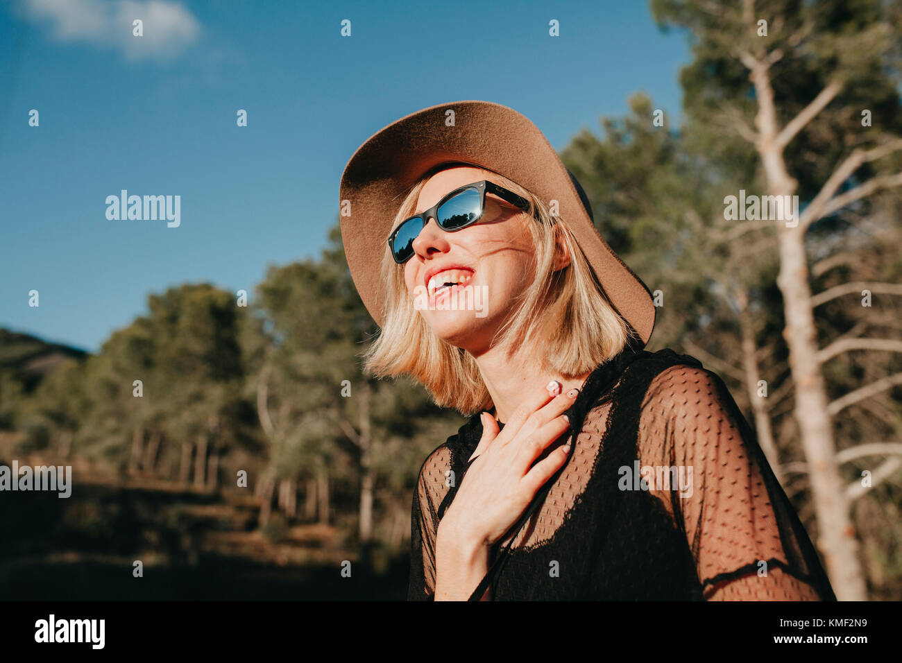 Felice donna bionda con occhiali da sole e un cappello per godersi la  natura in montagna Foto stock - Alamy