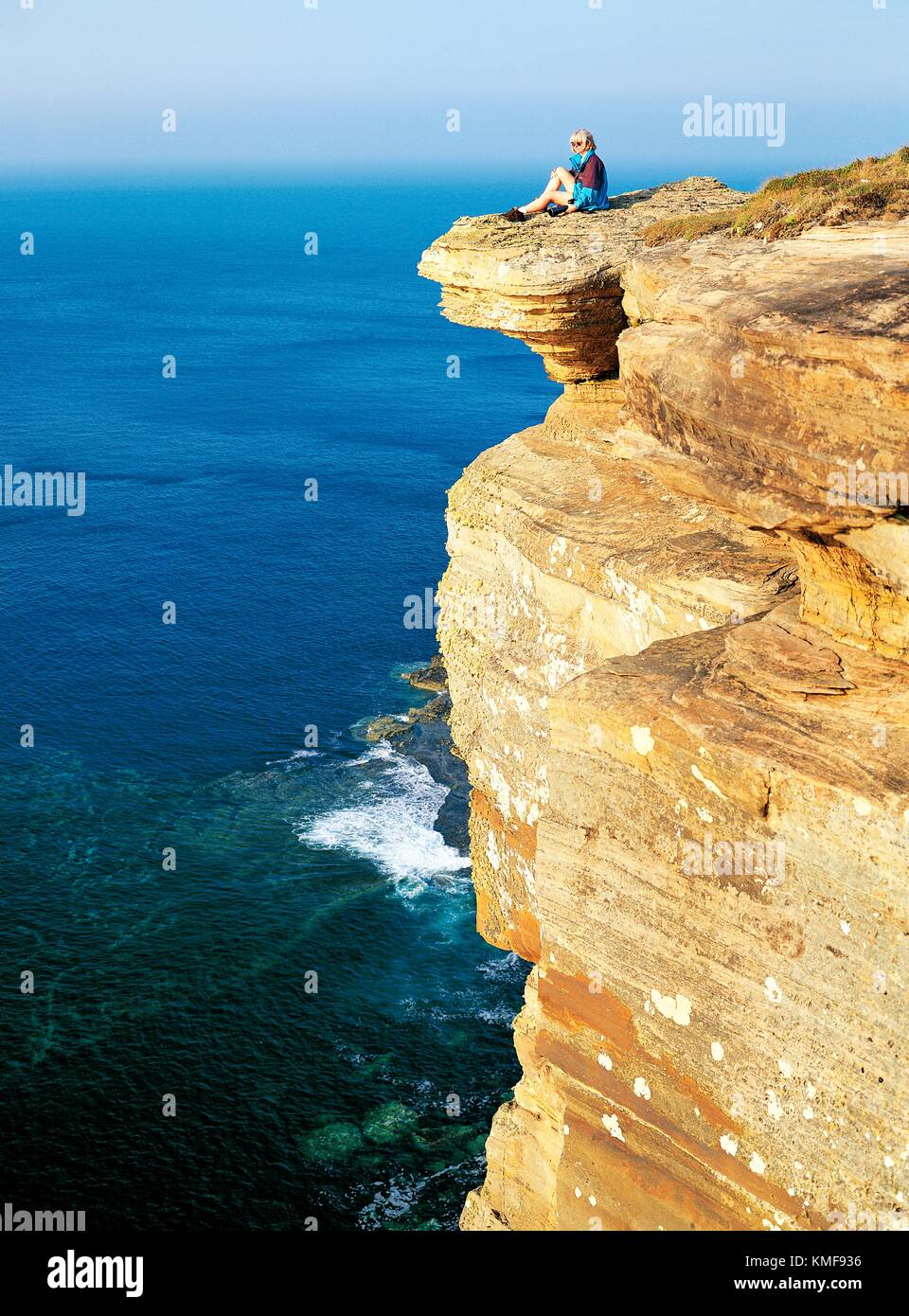 Giovane donna seduta su scogliere di Dunnett testa sopra Pentland Firth sulla costa nord di Caithness nella regione delle Highlands della Scozia Foto Stock
