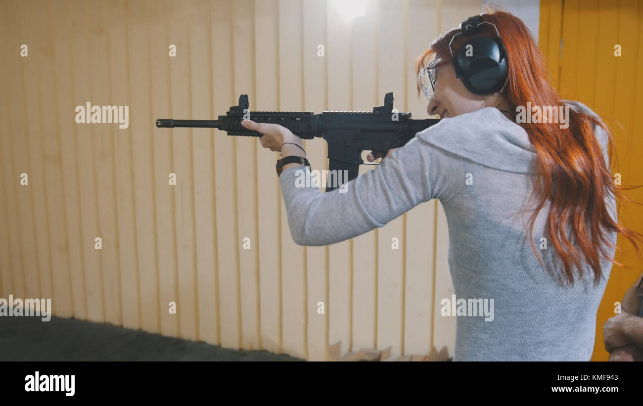La donna a sparare con una pistola mashin nella galleria di tiro Foto Stock