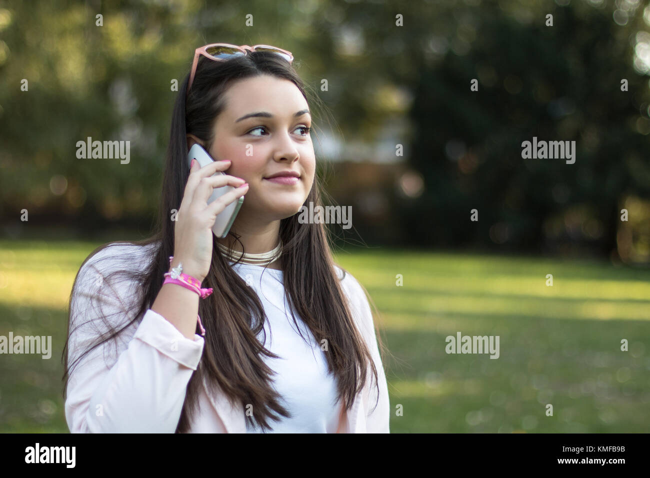 Giovane donna parlando sullo smartphone all'aperto in un parco Foto Stock