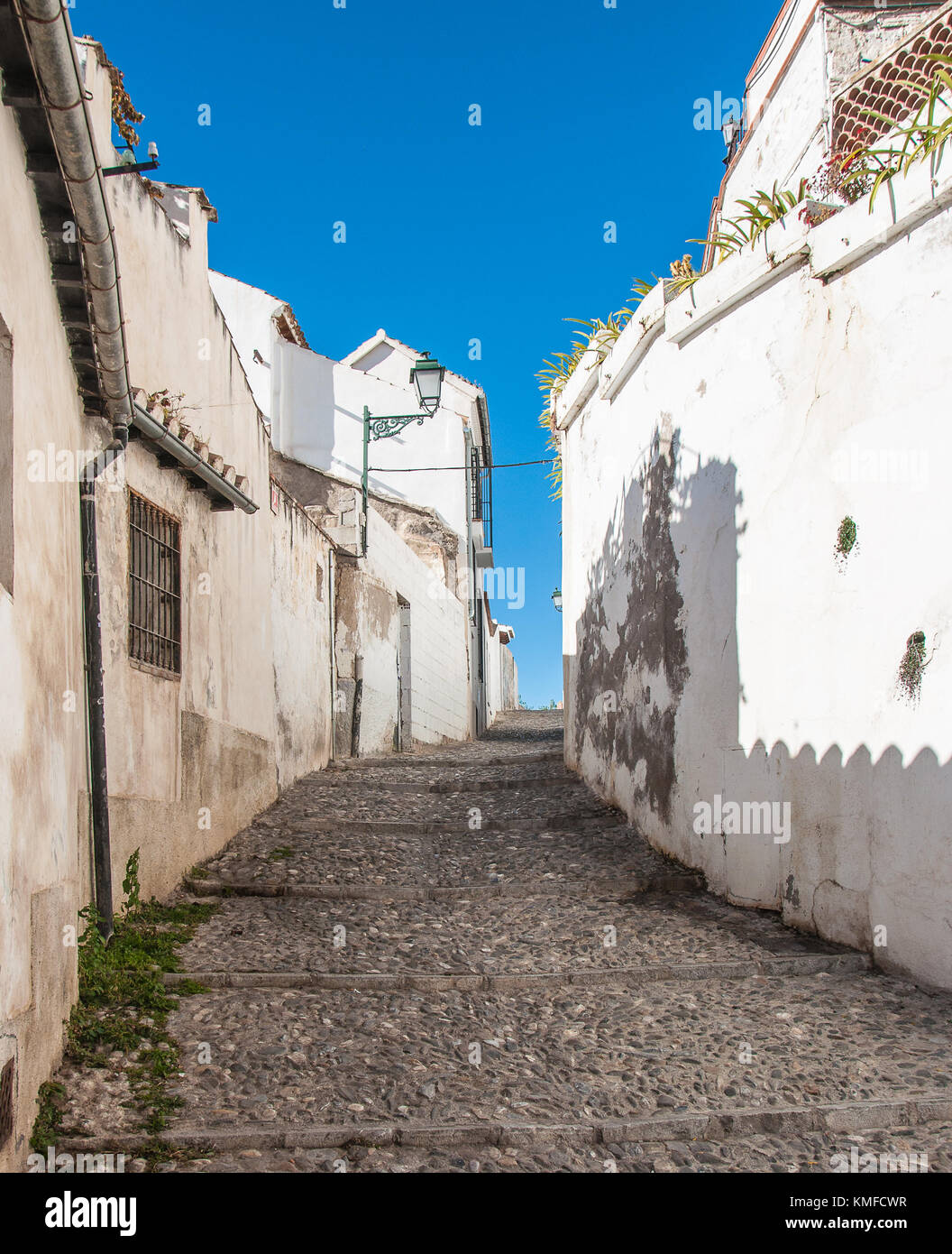 Una stretta viuzza acciottolata scalata al l'azzurro cielo privo di nuvole tra le tradizionali case dipinte di bianco. Foto Stock