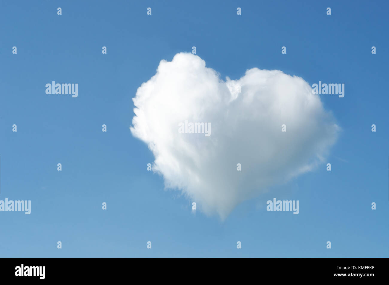 Un bianco a forma di cuore ad soffice nuvola in un altrimenti lucido chiaro cielo blu. Foto Stock