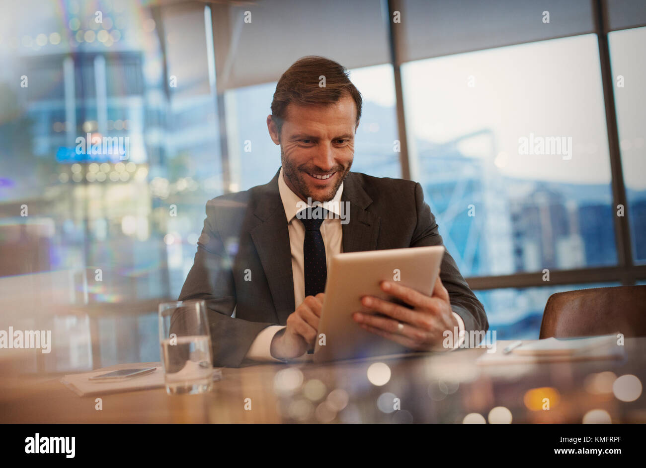 Uomo d'affari sorridente che utilizza un tablet digitale nella sala conferenze Foto Stock