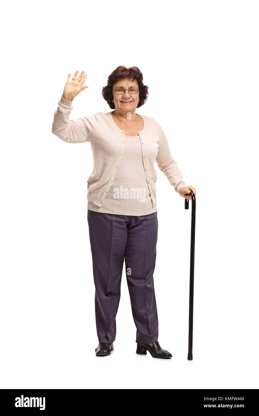 A piena lunghezza Ritratto di una donna anziana con una canna sventolando la fotocamera a isolati su sfondo bianco Foto Stock
