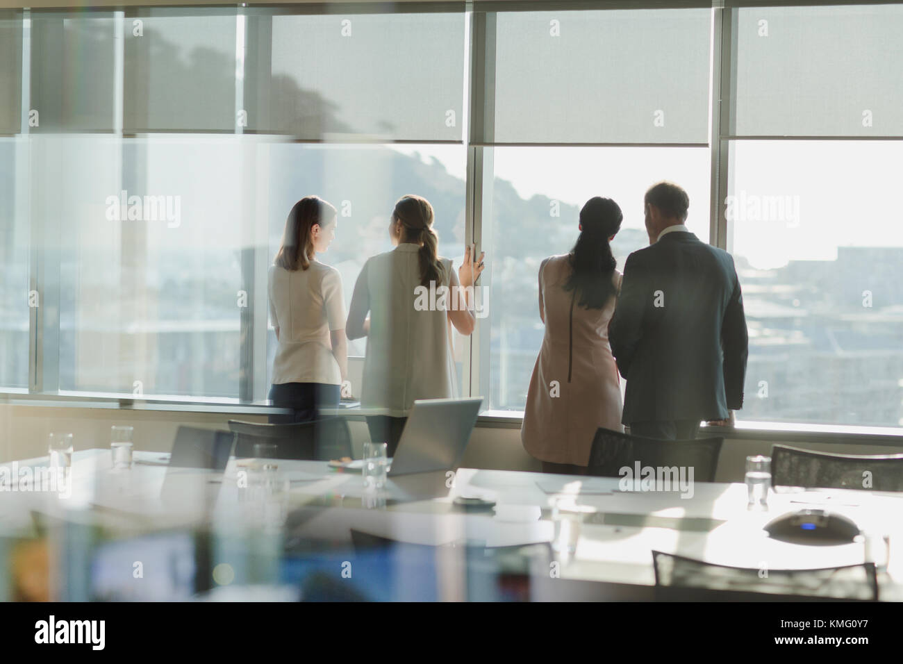 La gente di affari a guardare fuori dalla finestra di sole in ambiente urbano sala conferenze Foto Stock