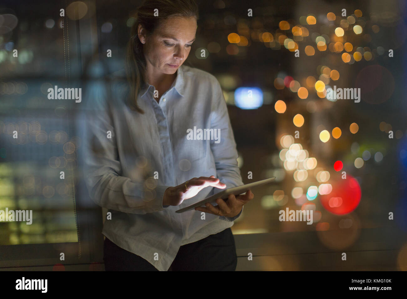 Donna d'affari che lavora tardi al tablet digitale in ufficio di notte Foto Stock