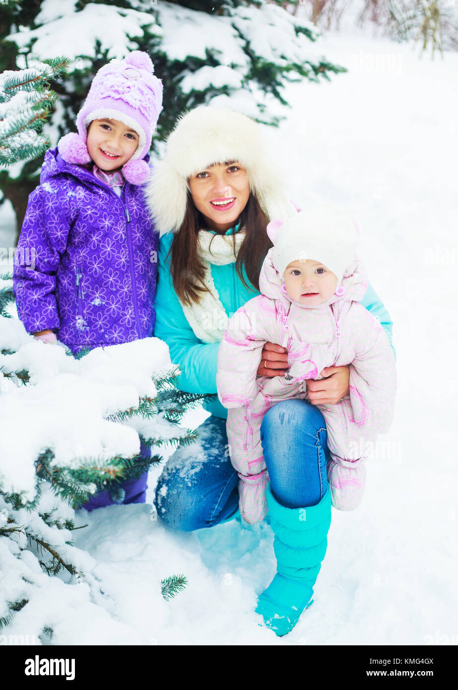 Felice giovane madre e le sue due figlie all'aperto nel parco invernale Foto Stock