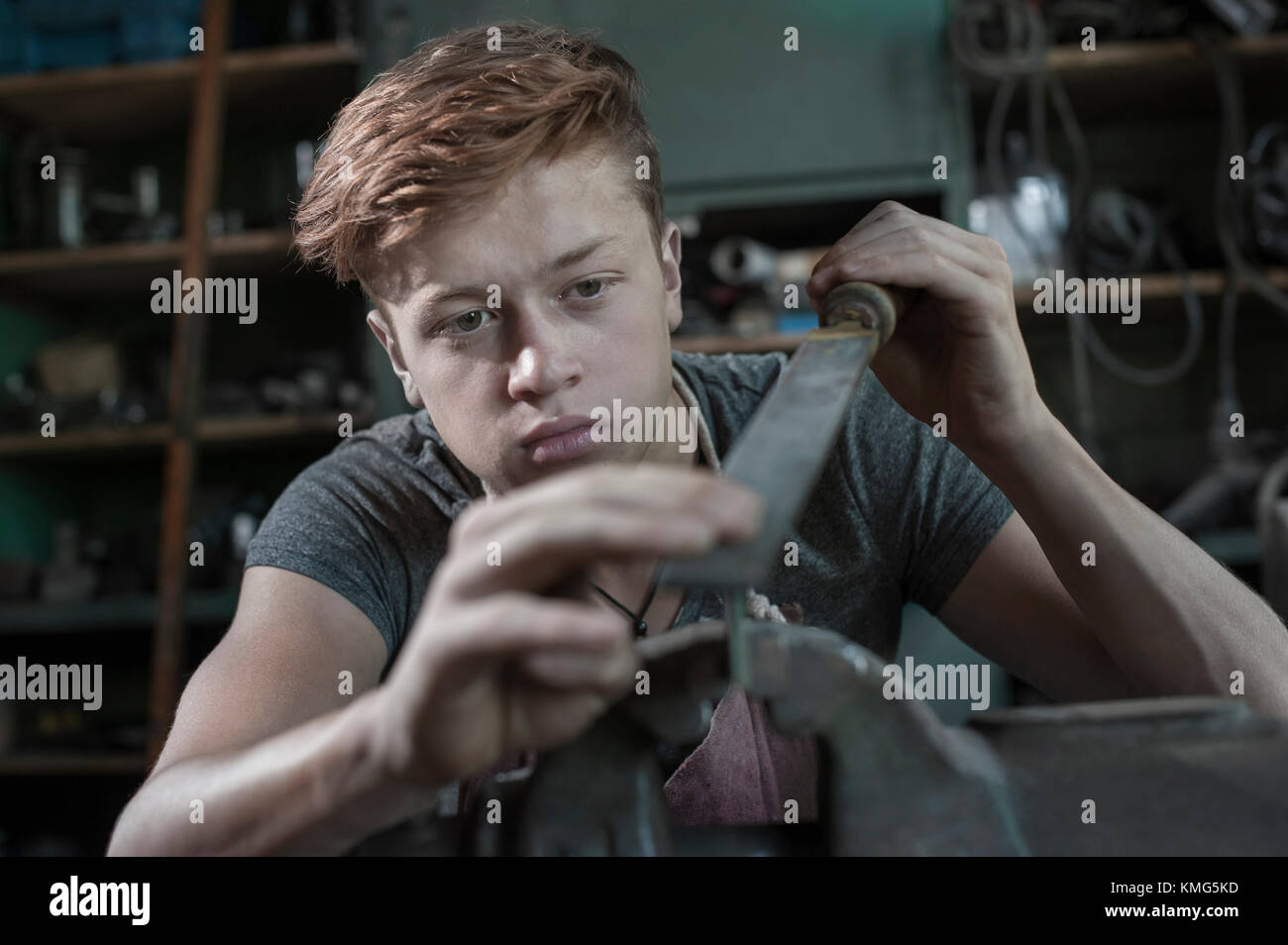 Fabbro apprendista raspante ferro fissato in morsa piana Foto Stock