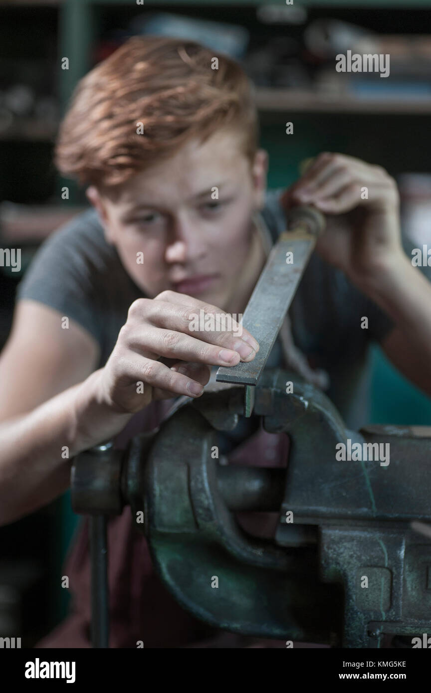 Fabbro apprendista raspante ferro fissato in morsa piana Foto Stock