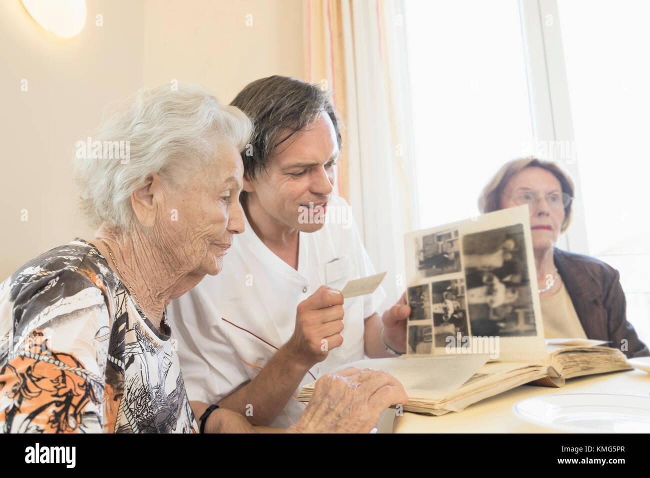 Custode che guarda le foto con la donna anziana a casa di riposo Foto Stock