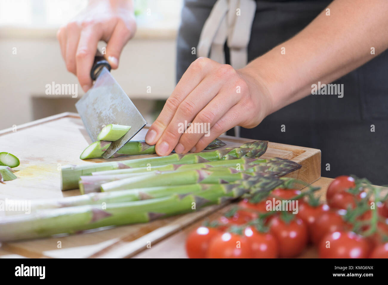 Uomo di asparagi di taglio sul pannello di legno Foto Stock