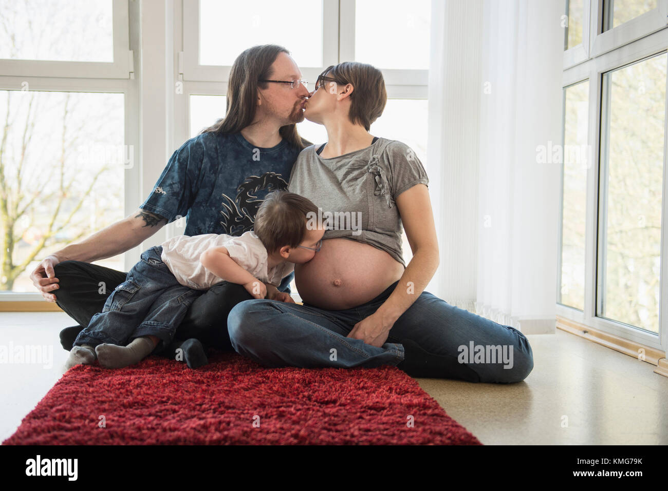 I genitori di baciare mentre figlio kissing in stato di gravidanza della madre ventre Foto Stock
