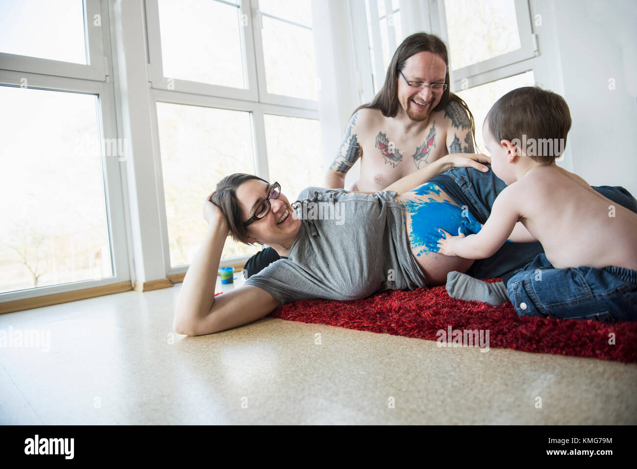 Il padre con il dito del figlio che dipinge il ventre della madre incinta Foto Stock