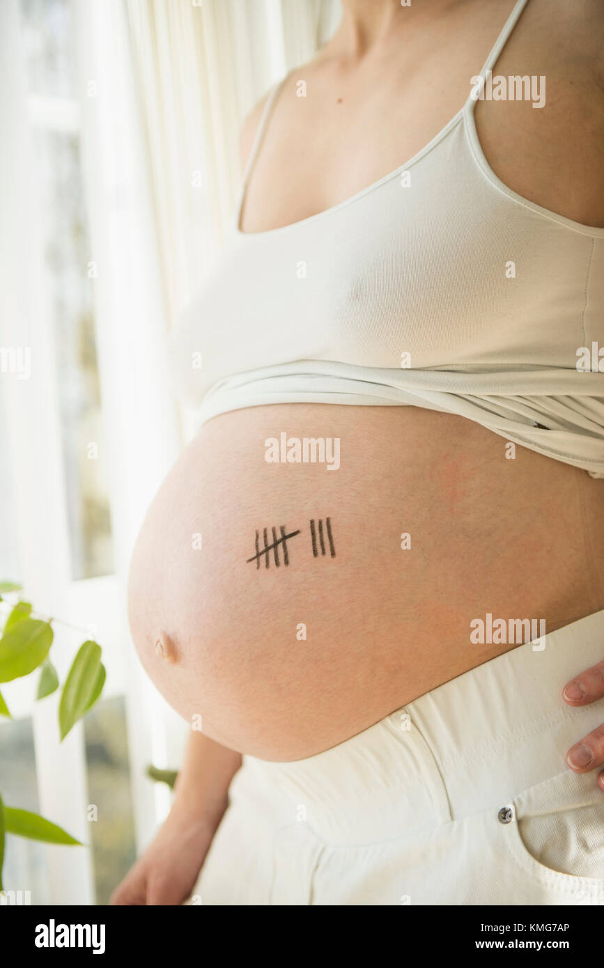 Donna incinta con il simbolo della carta tally sulla pancia Foto Stock