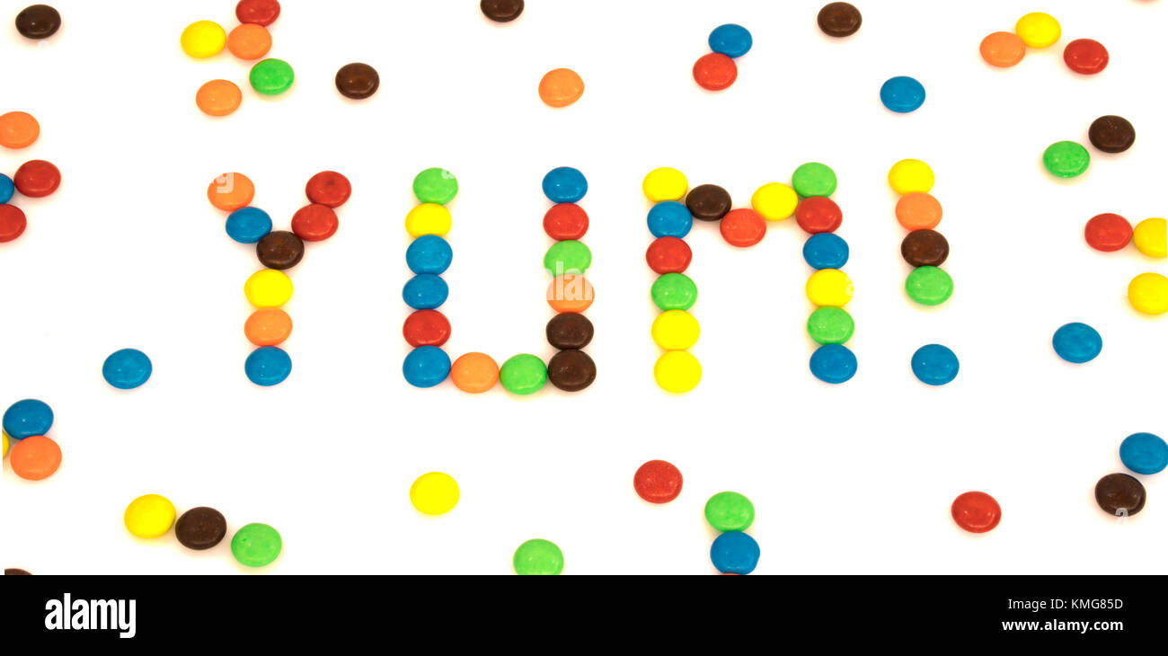 Yum parola scritta con colorate a forma di pulsante di cioccolatini candy isolati su sfondo bianco Foto Stock