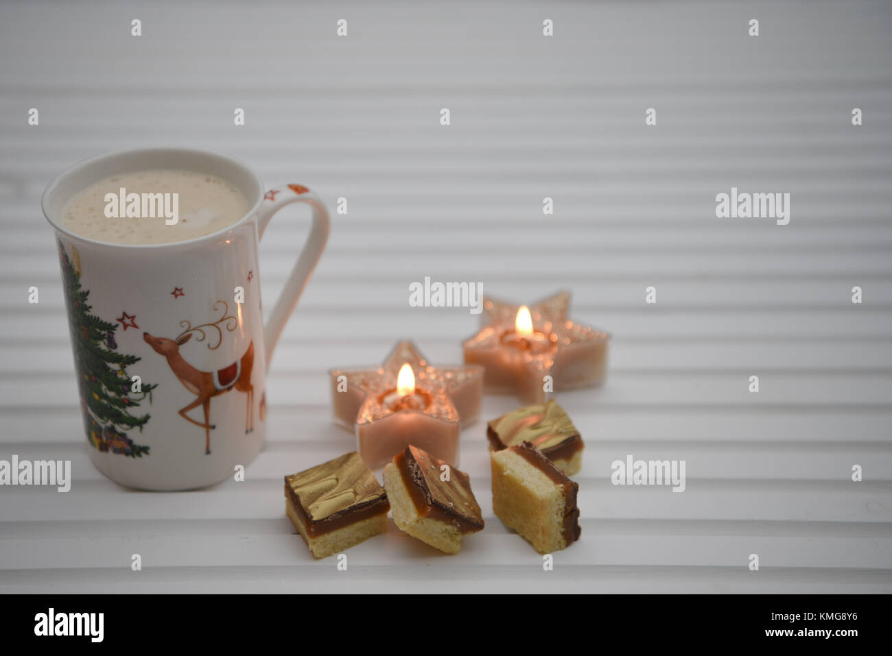 Natale immagine di fotografia con spumeggiante bevanda calda in renna boccale per stampa a caldo con candele e lusso alimentare al cioccolato bianco su uno sfondo di legno Foto Stock