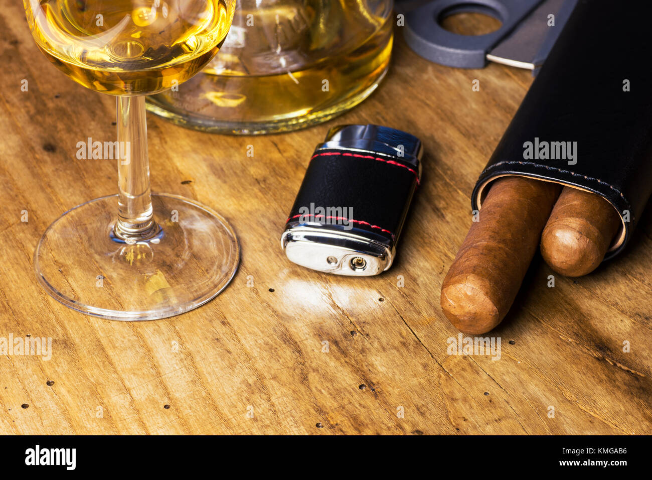 Custodia di pelle con i sigari, bottiglia e bicchiere di whiskey, più leggero e il coltello da caccia su una vecchia tavola di legno Foto Stock