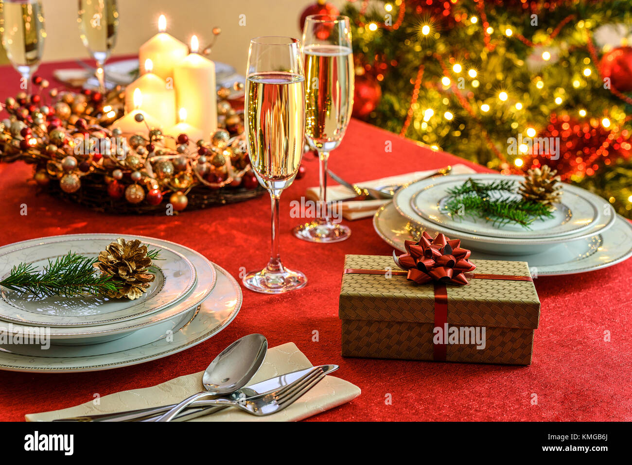 Splendidamente decorato tavola del Natale - regalo, bicchieri di champagne  e vasellame con decorazione di Natale su una tovaglia rosso Foto stock -  Alamy