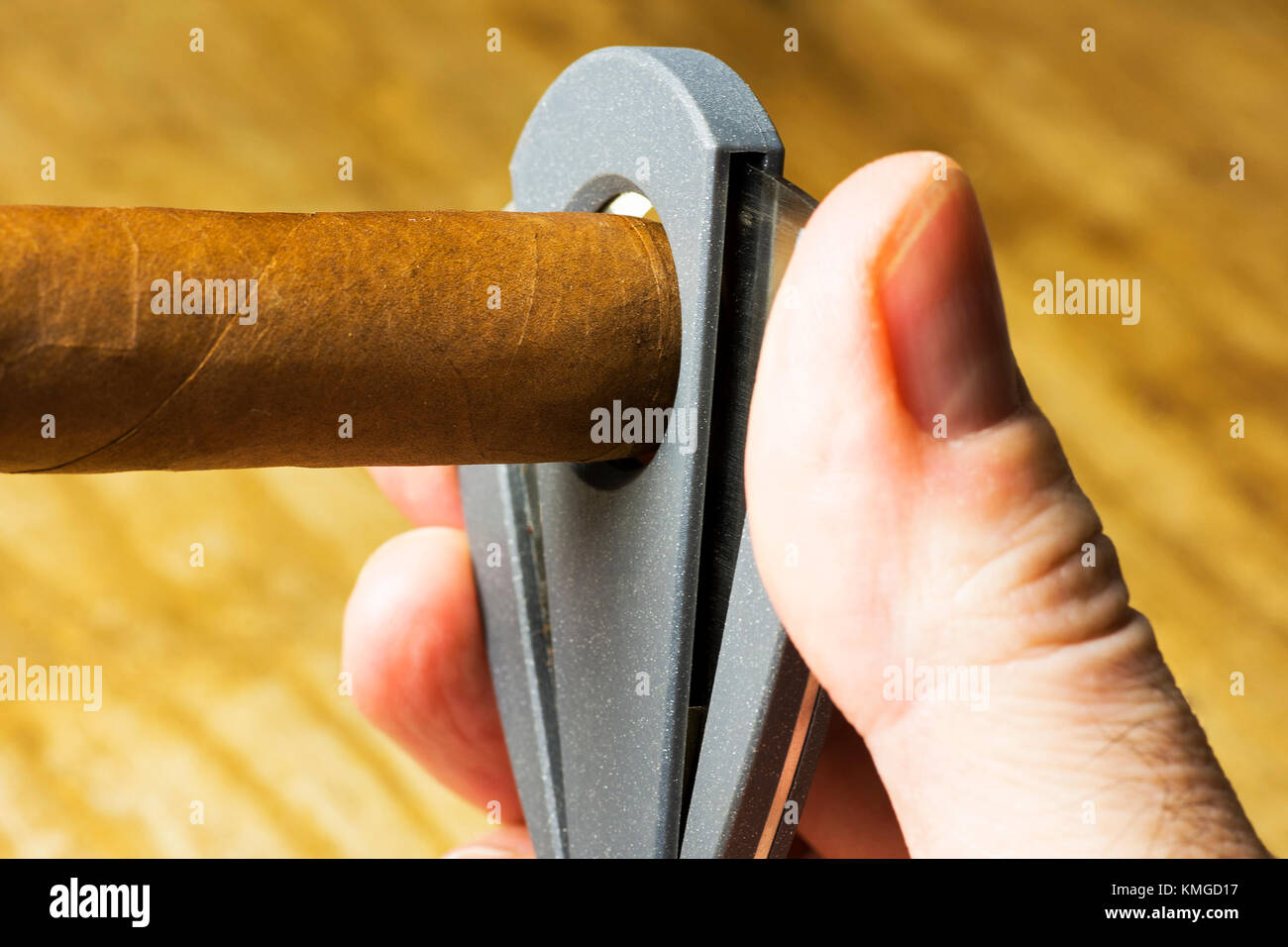 Mano d'uomo il taglio delle estremità di un sigaro con uno sfondo sfocato Foto Stock