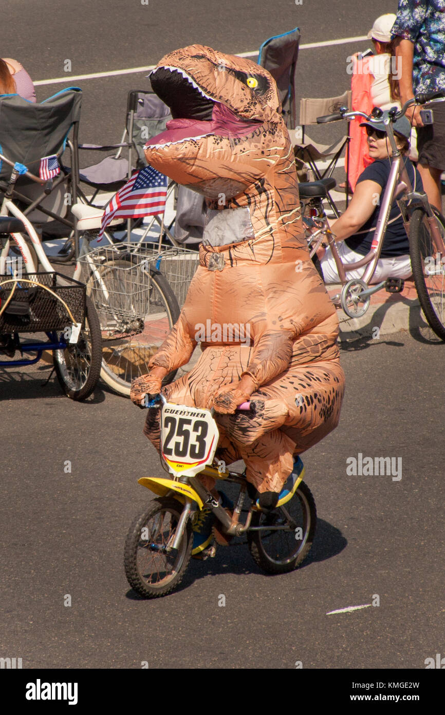 Un ciclista in un tirannosauro Rex costume di dinosauri pedali attraverso Huntington Beach, ca. Foto Stock
