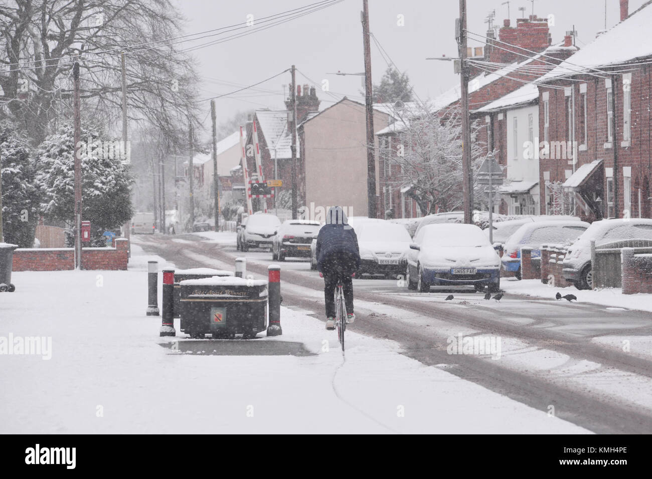 Ciclista in inverno la neve, Willaston, Nantwich, Cheshire, Regno Unito. Foto Stock