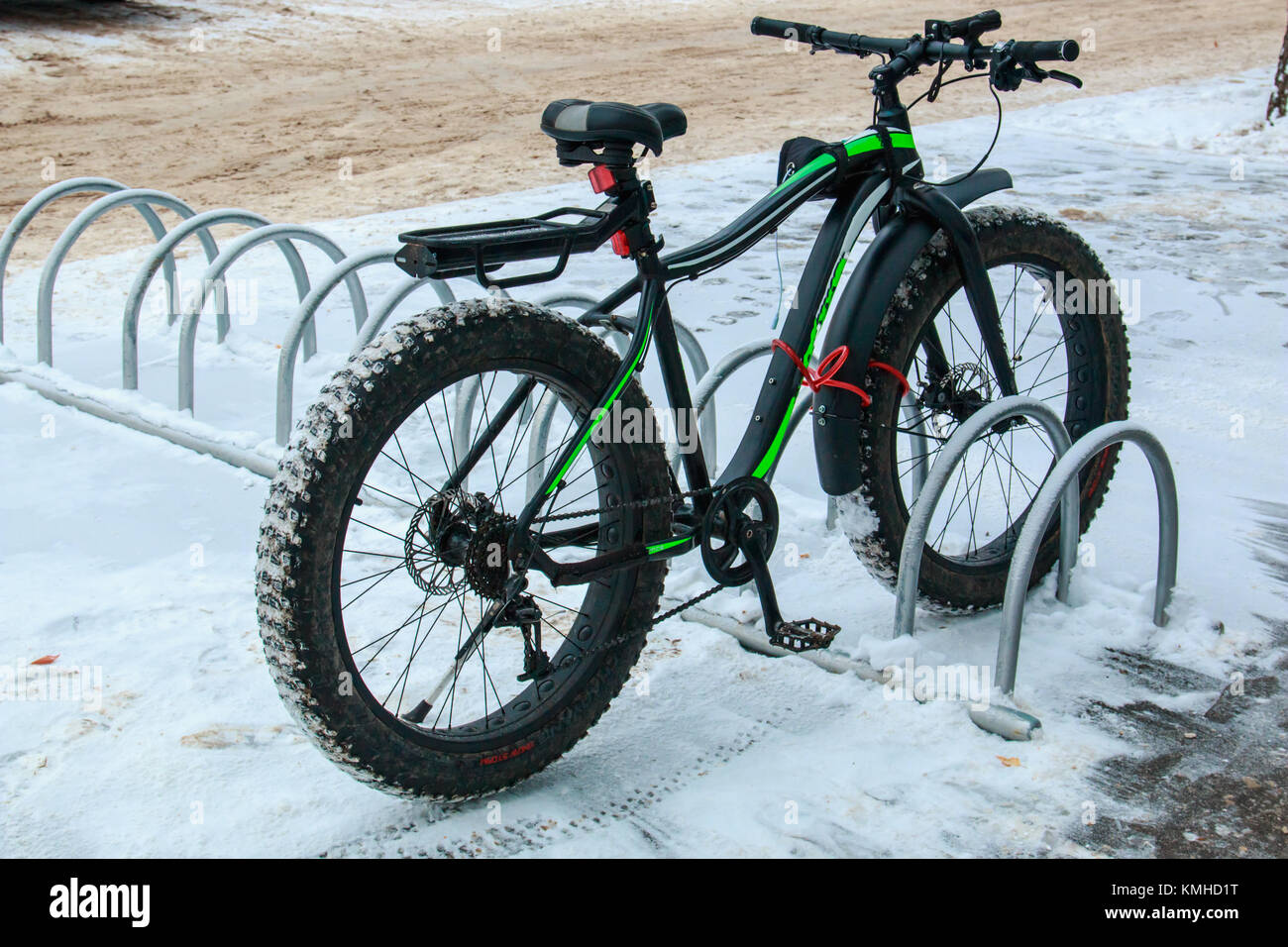 Bicicletta con una vasta gomma nel parcheggio vicino al negozio in città in inverno. Foto Stock