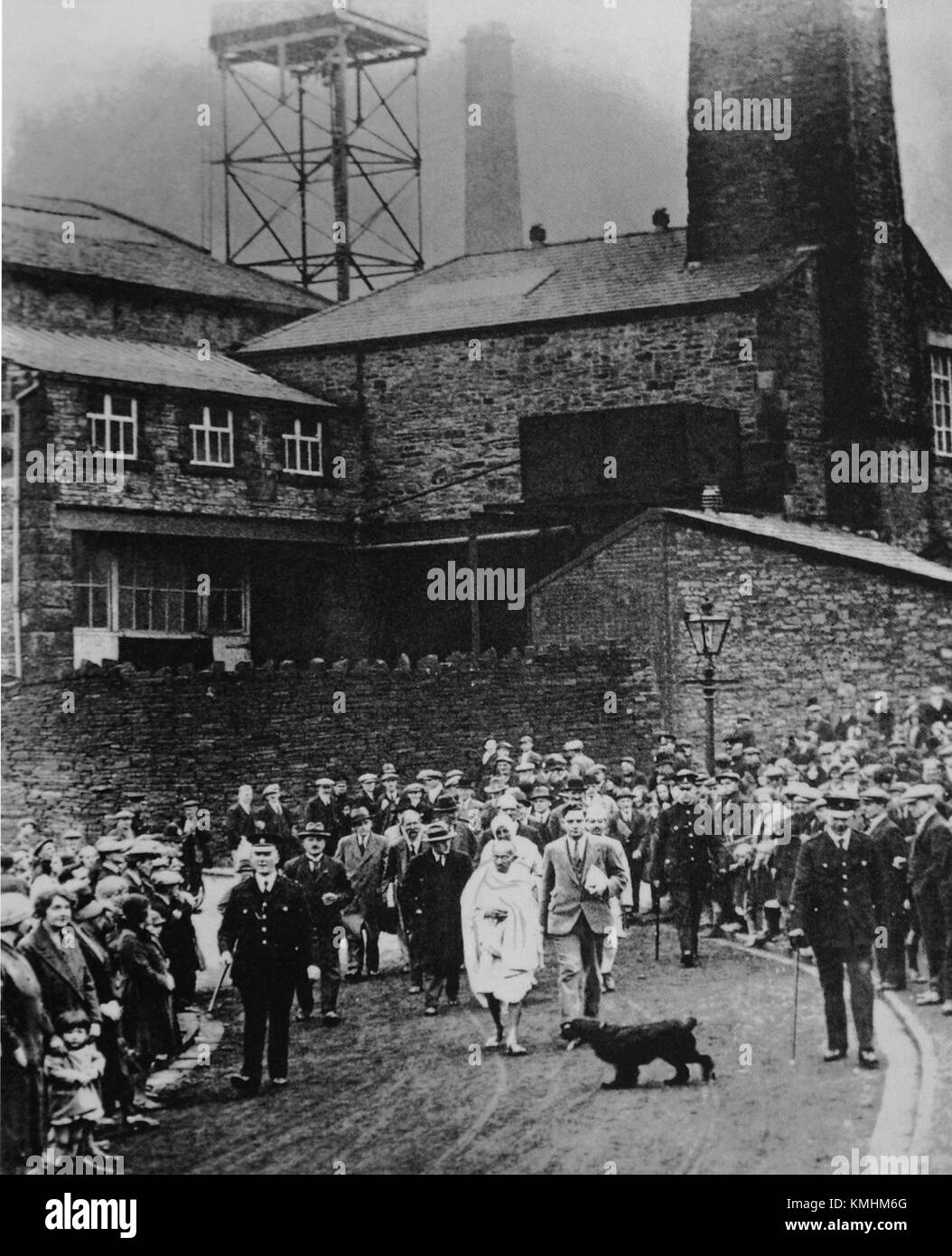 Mahatma Gandhi viene mostrato in visita a una fabbrica tessile, sottolineando la sua attenzione all'autosufficienza e al progresso industriale dell'India. Questa immagine sottolinea il suo ruolo nella promozione del movimento indipendentista indiano e nel sostegno alle industrie locali. Foto Stock