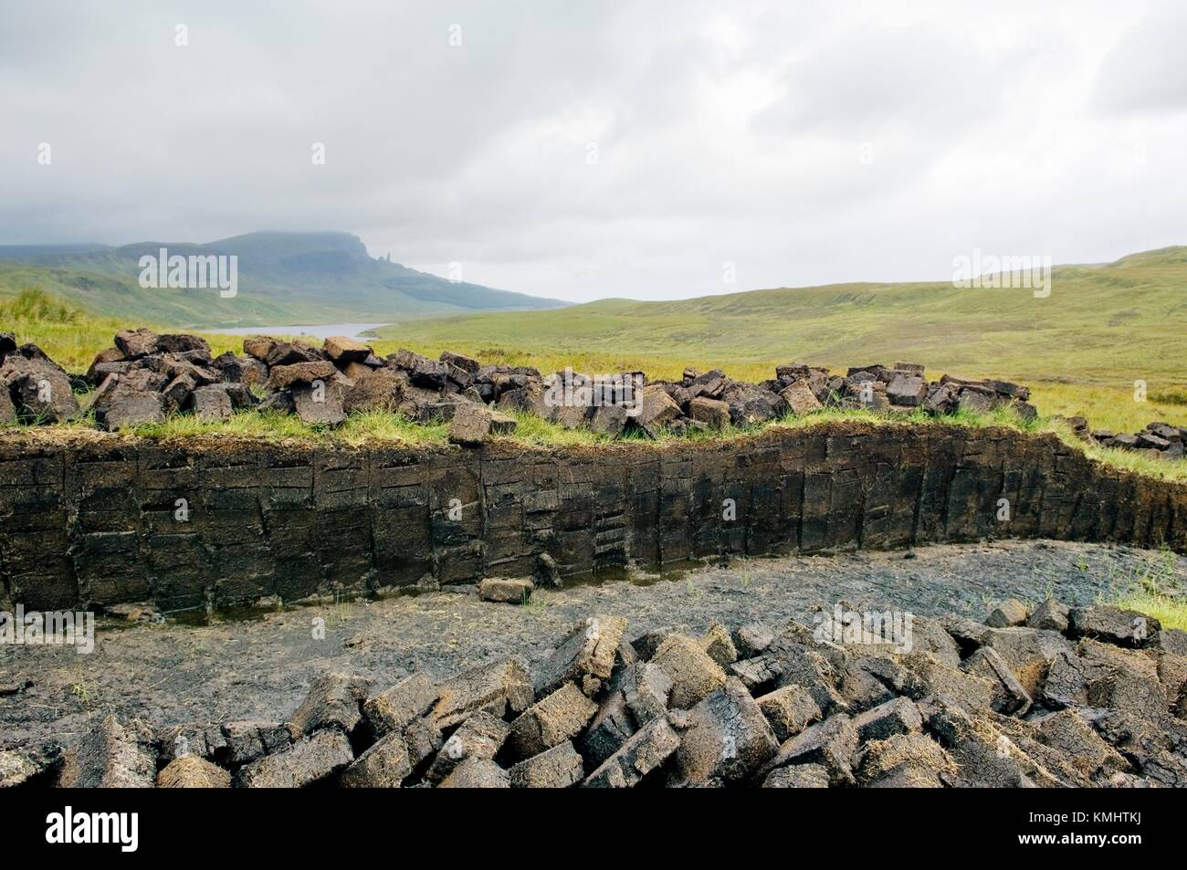 Trotternish, Isola di Skye in Scozia. Tappeto erboso di torba Bank a tagliare per il carburante sopra Loch Fada. Pinnacolo di roccia del Storr a distanza Foto Stock