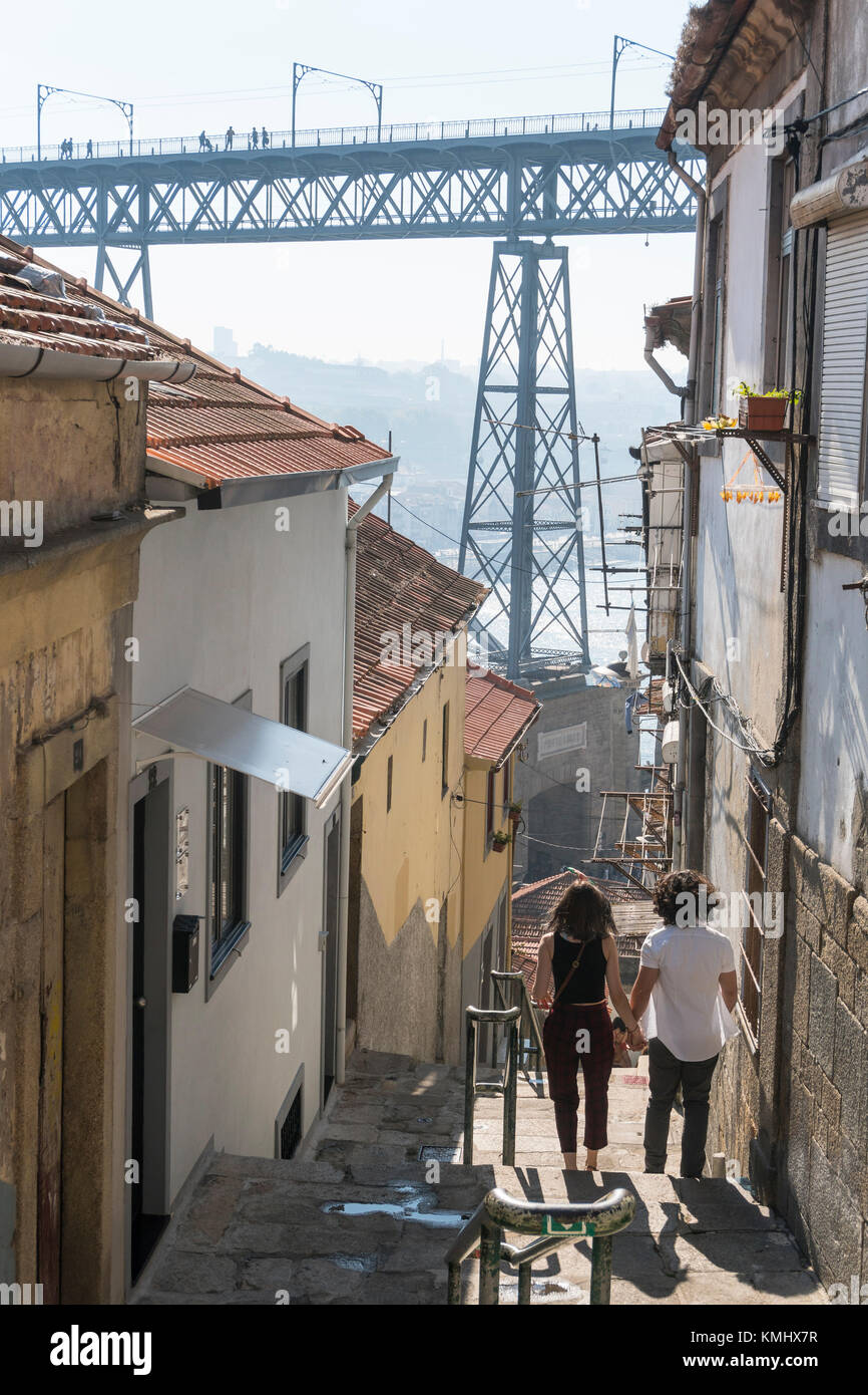 Le fasi che conducono in basso verso il fiume Douro lungomare nel quartiere Ribeira di Porto, Portogallo. con il Dom Luis I Bridge in background. Foto Stock