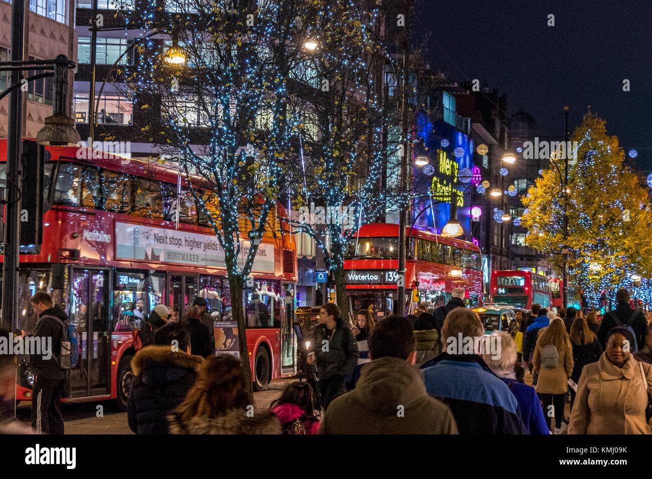 Una linea di autobus londinesi su Oxford St con il marciapiede occupato dai clienti di Natale, Londra, Regno Unito Foto Stock