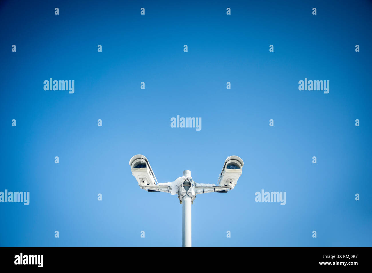 Le telecamere di sicurezza contro il cielo blu, il bianco delle telecamere con un po' di neve sulla parte superiore, la simmetria Foto Stock