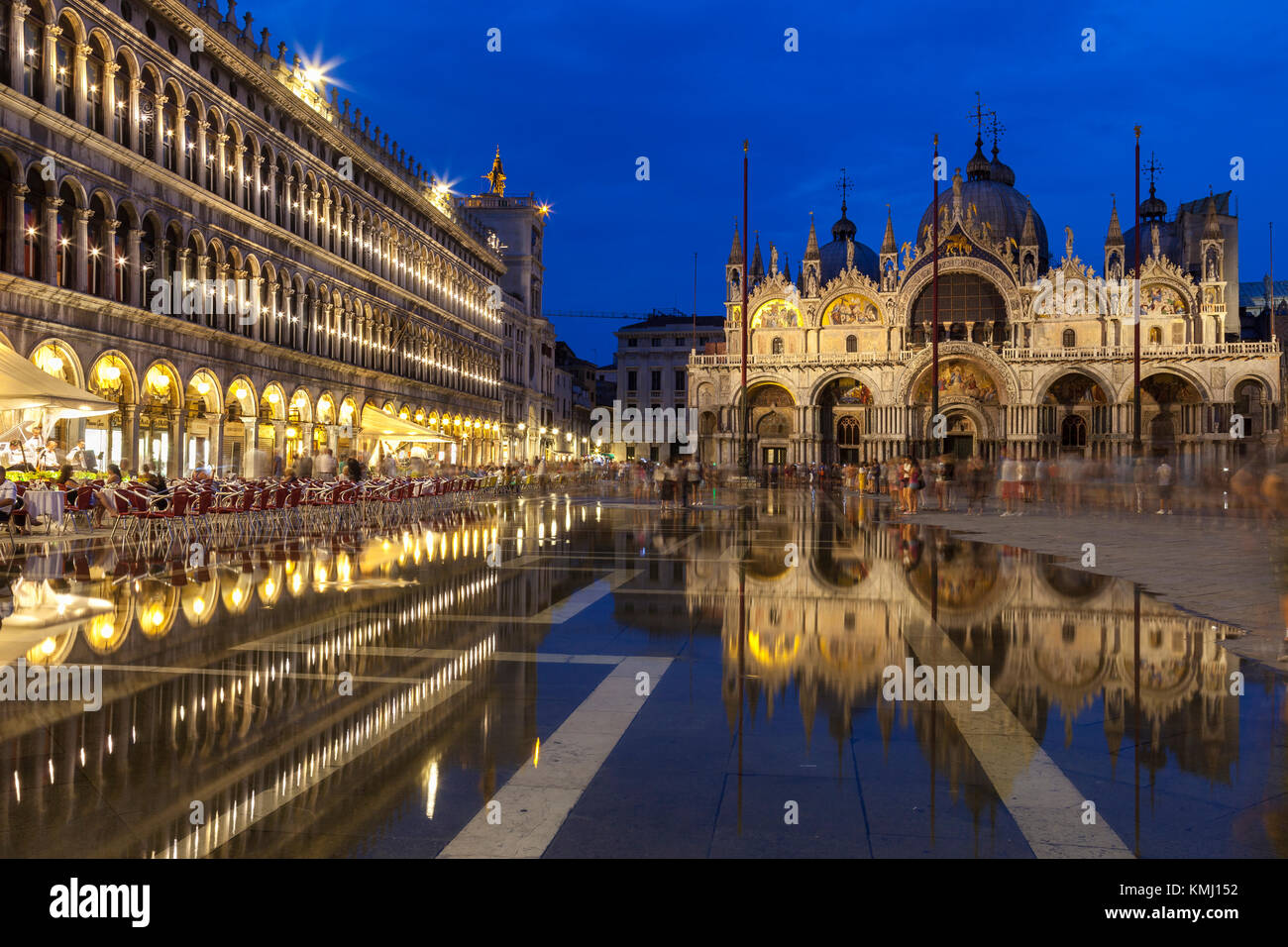 Basilica di San Marco si riflette in acqua alta in Piazza San Marco al crepuscolo durante ore blu , Venezia, Italia con motion blur su folle di turisti Foto Stock