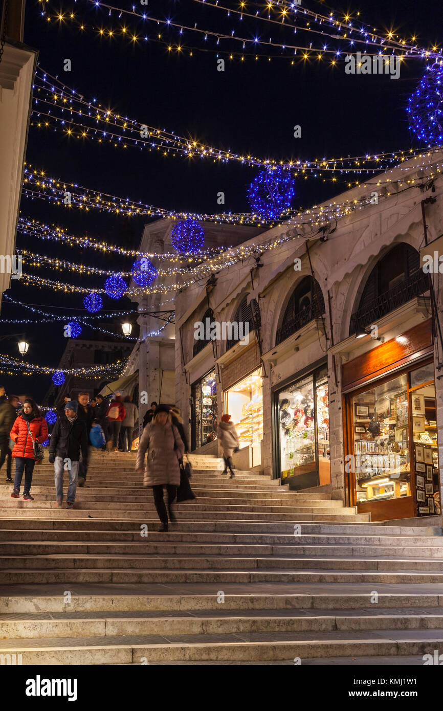 Accese le luci di Natale sul Ponte di Rialto, Venezia, Italia di notte con luminose negozi e persone che camminano giù i passaggi Foto Stock