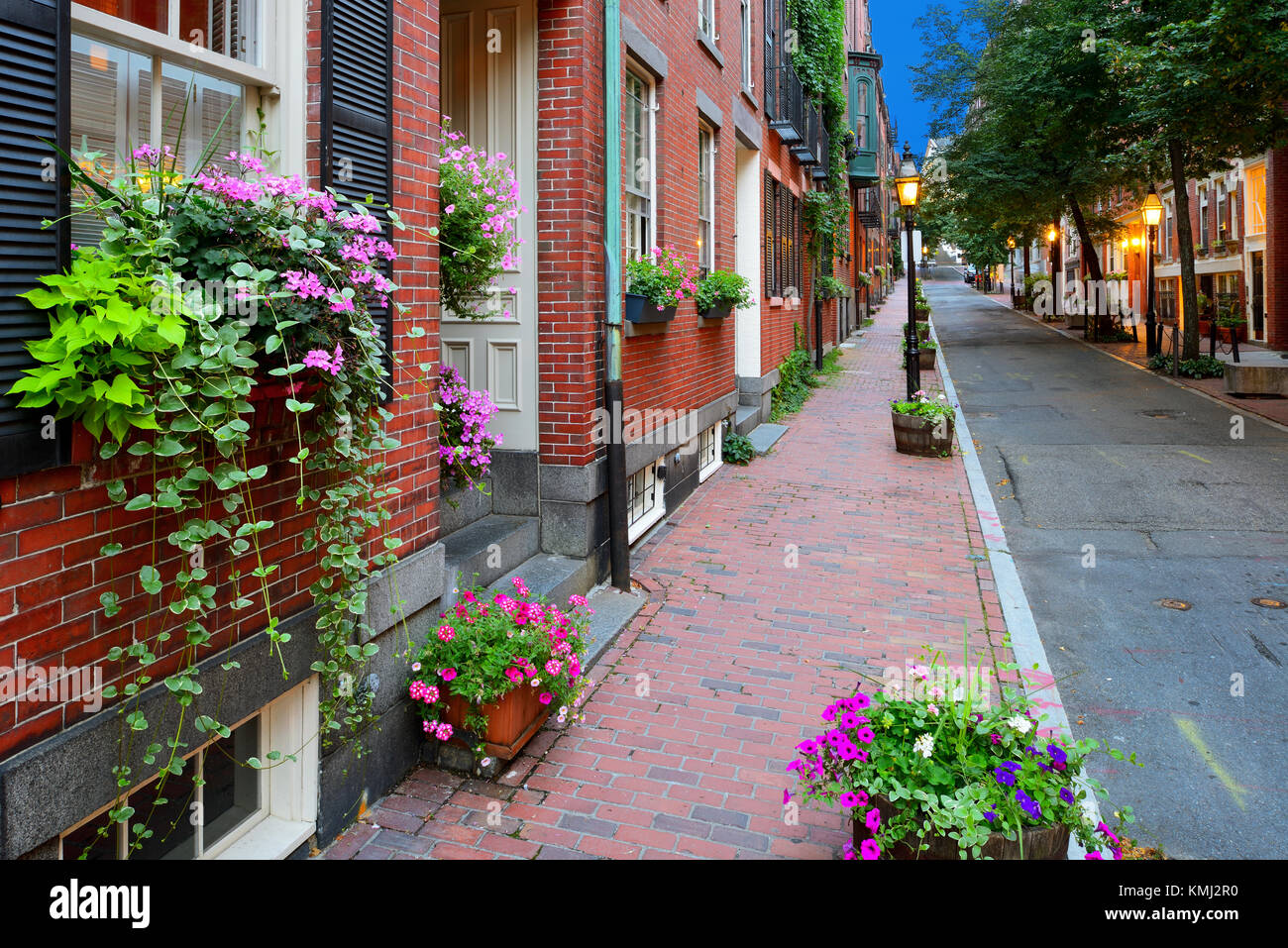 Suggestiva strada in Beacon Hill, Boston. palazzi in mattoni rossi e marciapiedi e lampioni, scatole di finestra e piantatrici, scena notturna. Foto Stock