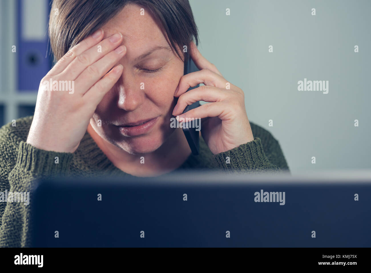 Stanco esausto freelancer femmina parlando al telefono mobile dalla sua propria start up business home office Foto Stock
