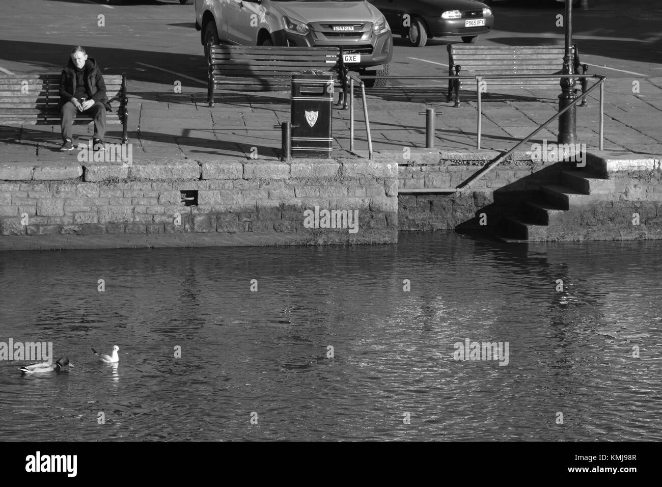 Uomo seduto da fiume a guardare le anatre Foto Stock
