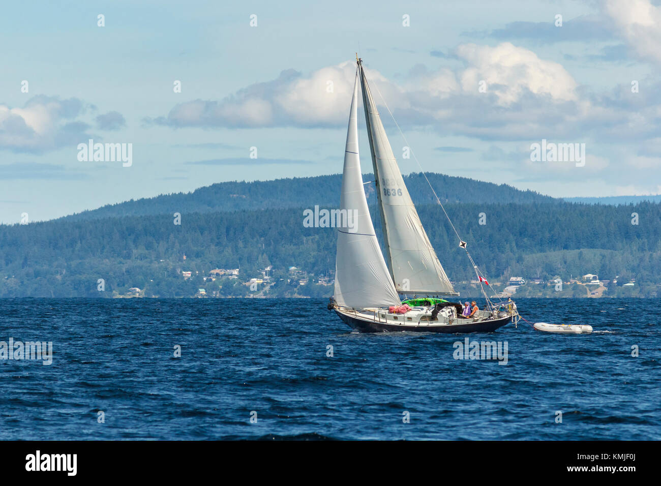 In un giorno di estate, una coppia di mezz'età sono al timone di un canadese yacht a vela in stretto Malaspina, vicino a Powell River, British Columbia. Foto Stock