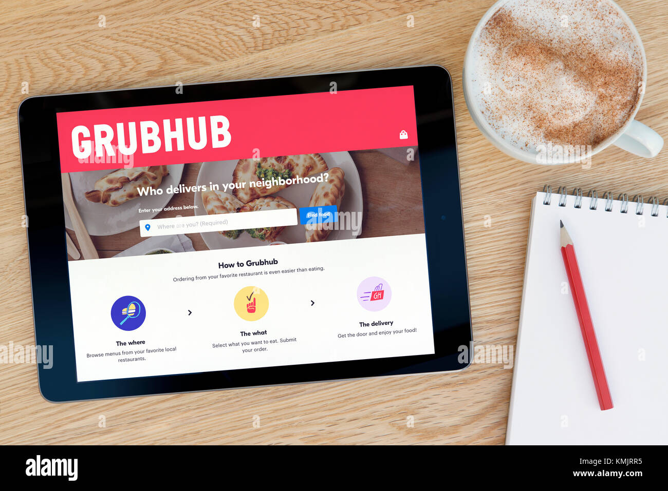 Il sito web GrubHub funzioni su un iPad dispositivo tablet pc che si appoggia su una tavola di legno accanto a un blocco note e matita e una tazza di caffè (editoriale solo) Foto Stock