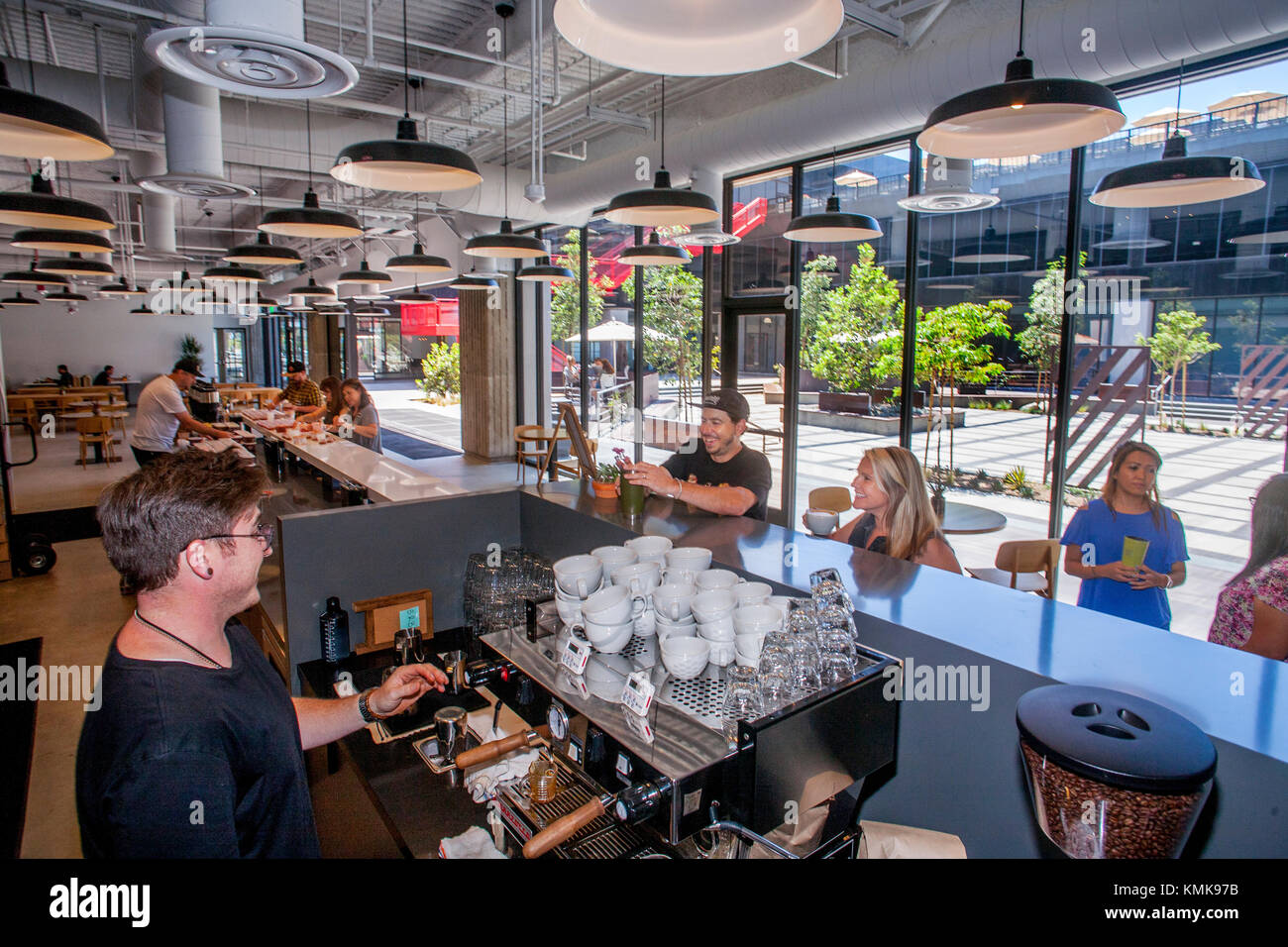 Un full time barista rende libera le bevande a base di caffè per i dipendenti al vans scarpa azienda sede aziendale di Costa Mesa, CA. Nota cortile centrale in background. Foto Stock