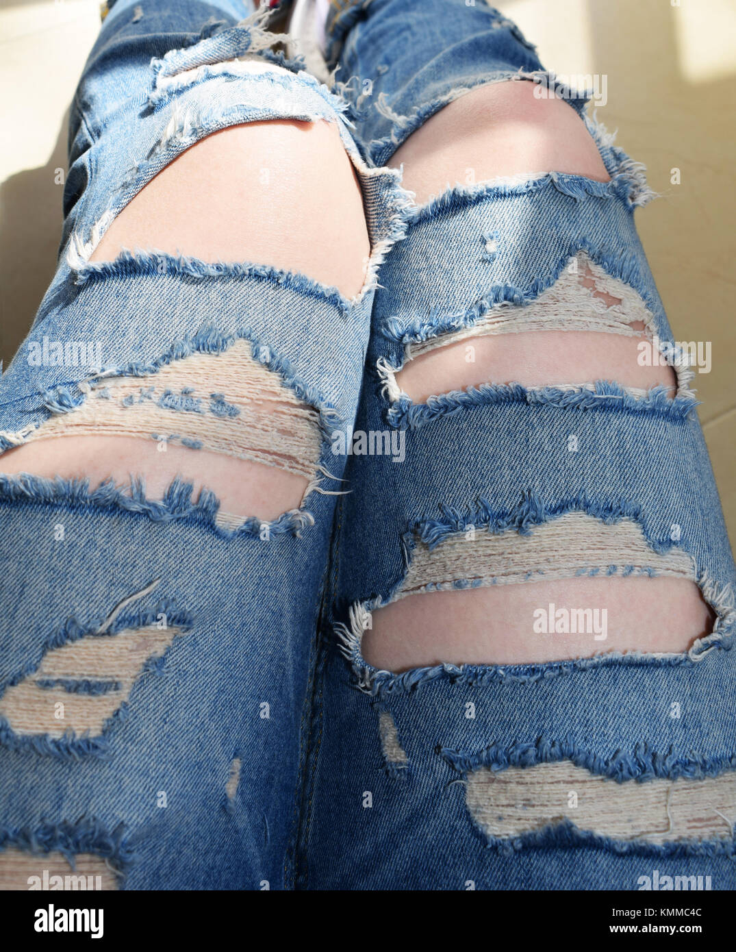 Jeans strappati con gamba che mostra la pelle Foto Stock